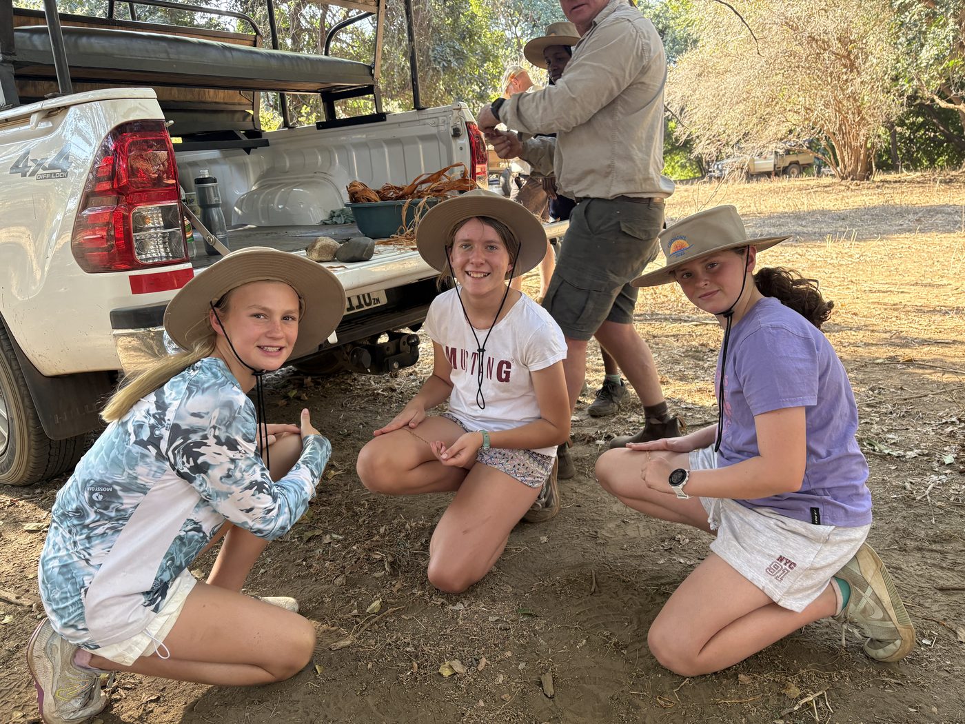 Three Musikili pupils in sun hats on a field trip to Chongwe
