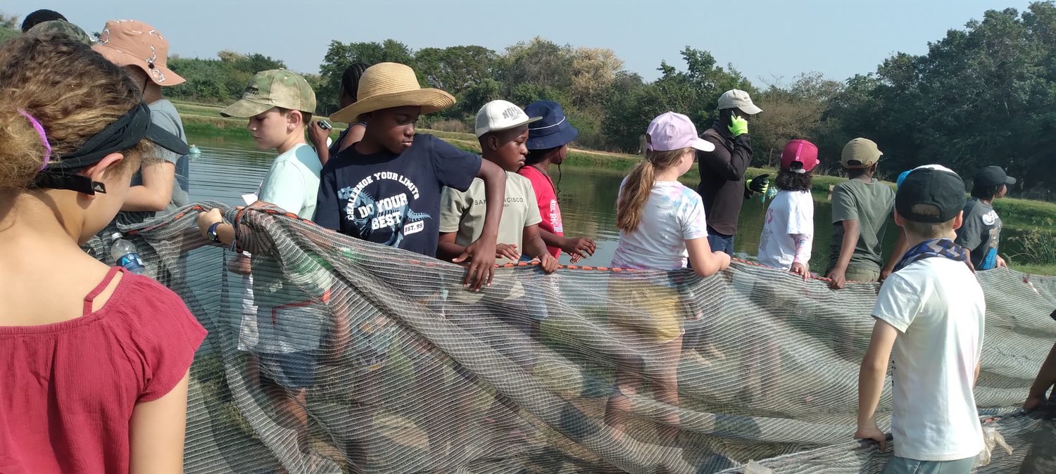 Grade 4 pupils hauling a fishing net at the water at Sinazongwe